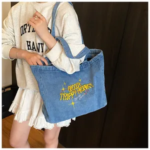 Detail of yellow embroidery on a blue denim tote bag featuring Groovy Trippy Heart text