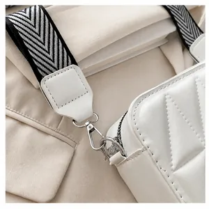 Detailopname van witte leren tas met V-stiksel en zilveren metalen haaksluiting