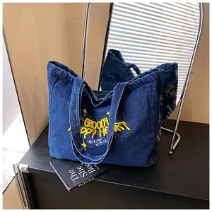 Detail of vintage yellow embroidery and star motifs on deep blue denim tote bag