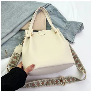 Detail of cream bucket bag showing pebble leather texture and ethnic embroidery strap