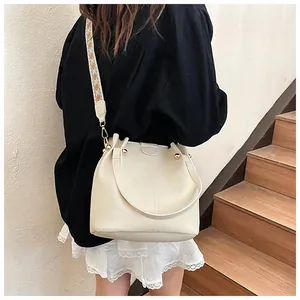 Detail of cream bucket bag with lychee texture leather and geometric woven strap
