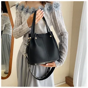 Detail of black pebbled leather bucket bag featuring a jacquard woven wide shoulder strap