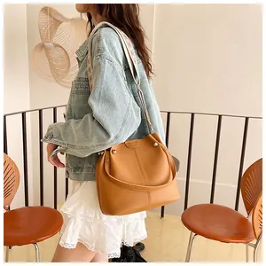 Close-up of caramel leather bucket bag featuring a textured finish and geometric wide strap