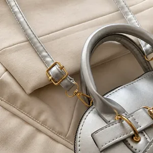 Detail of silver shell bag showing adjustable gold buckle and precise stitching