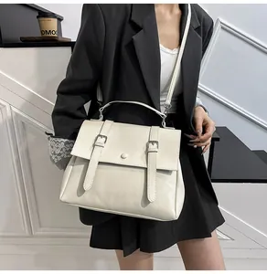 Modella che indossa una borsa messenger vintage crema in un interno minimalista con scale