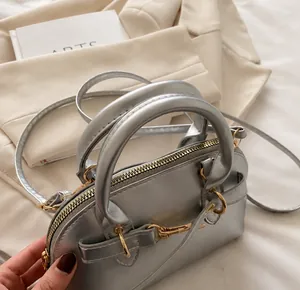 Close-up of comfortable double handles and gold metal zippers on silver shell bag