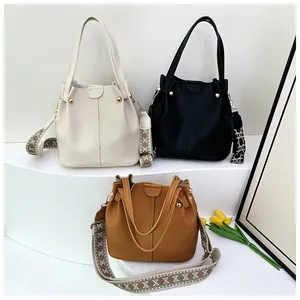 Three leather bucket bags in beige, black, and brown with patterned wide woven straps