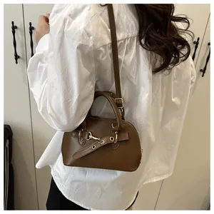 Side view of a vintage brown shell bag with metal hardware and adjustable strap