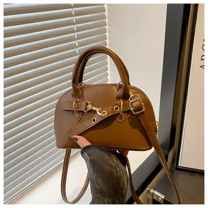Detailed view of a vintage brown shell handbag with metallic buckle and leather strap