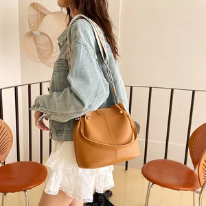Caramel brown pebbled leather bucket bag with ethnic print wide strap and rivets