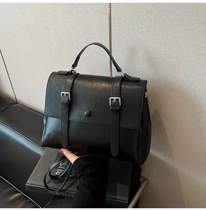 Dettaglio della borsa a tracolla in pelle nera vintage con fibbie argentate e manico