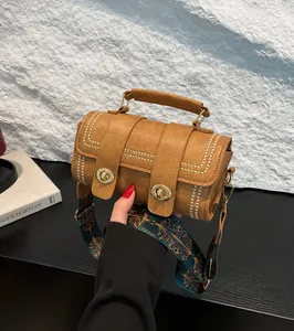 Detail of khaki pebbled leather cylinder bag with colorful bohemian wide shoulder strap