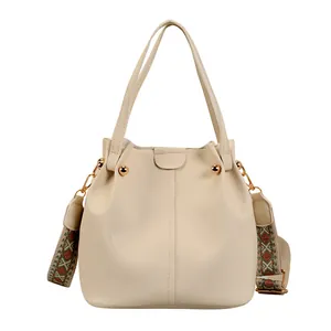 Beige bucket handbag in pebble leather with a wide ethnic style embroidered strap