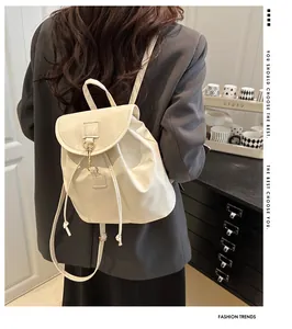 Sac à dos chic en cuir beige avec cordon et rabat porté par une femme à l'arrière