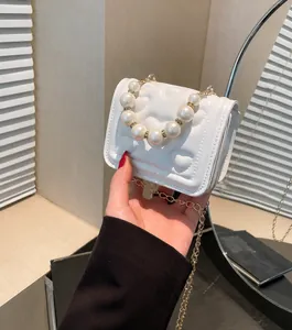 Detail van witte PU-lederen mini-handtas met hartstiksel en parel handvat