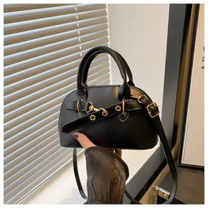 Detailed macro view of black faux leather shell bag with elegant gold hardware accents