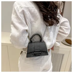 Dettaglio della mini borsa a trapezio nera con catena in metallo e manico rotondo