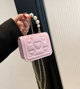 Detail van roze mini-tas met hartjesreliëf, parelhandvat en gouden metalen ketting