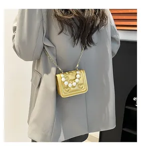 Detail of gold heart-quilted mini bag with pearl handle and metal chain strap