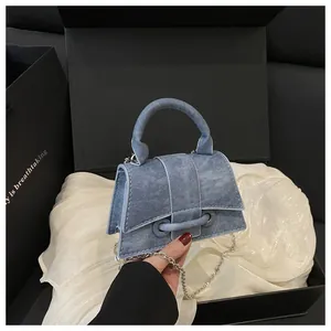 Dettaglio mini borsa in denim azzurro con catena argento su sfondo di seta bianca