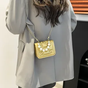 Mini metallic gold crossbody bag with heart embossing and pearl handle on model