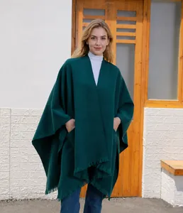 Nahaufnahme des dunkelgrünen Capes mit Fransensaum und großen Taschen für Herbstmode