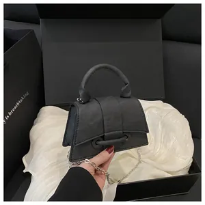 Dettaglio di mini borsa nera testurizzata con catena argento e confezione regalo elegante