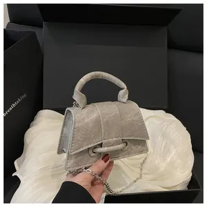 Vista macro della mini borsa argento con tracolla a catena e design a trapezio