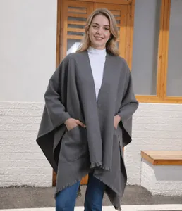 Detail eines dunkelgrauen Strickponchos mit großen Taschen und Fransen am Saum