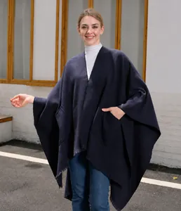 Detail eines dunkelblauen Strickponchos mit praktischen Taschen und Fransenkanten