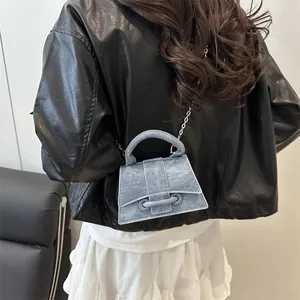 Piccola borsa a trapezio in denim azzurro con catena d'argento su una modella
