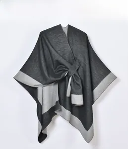 Detail of grey split knit poncho shawl featuring metal buckle closure and fine texture