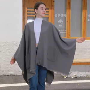 Mittlerer grauer Strickschal mit Taschen und Fransen über einem Freizeitoutfit