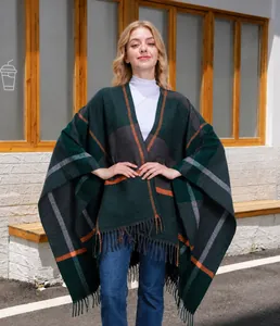 Detail eines grünen Karoponchos mit orangen Akzenten und Fransen für den Winter-Look