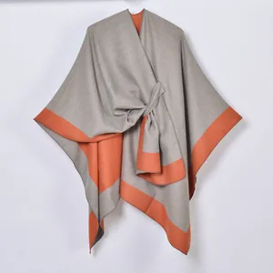 Detail showing soft gray and orange knit texture with knotted design on split shawl