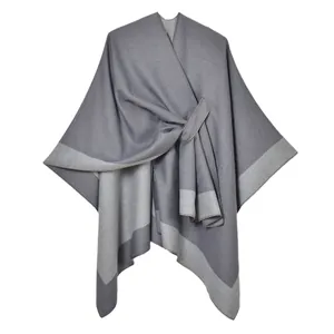 Detail of grey cashmere-like split poncho showing soft knit texture and ring buckle closure