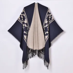 Women knit poncho featuring navy and beige geometric jacquard patterns with fringed hem