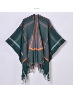 Detail eines karierten Ponchos mit orange-grünen Linien und Fransen am unteren Saum