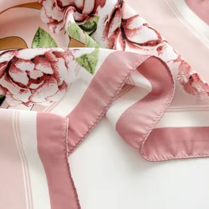 Dettaglio foulard in seta rosa con eleganti stampe floreali e bordi arrotolati a mano