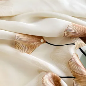 Détail d'un foulard en soie avec motif élégant de feuilles de ginkgo sur tissu beige