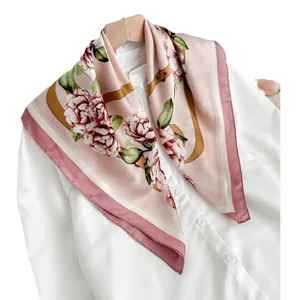 Sciarpa in seta rosa con motivo floreale su camicia bianca e gruccia in legno chiaro