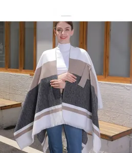 Detail of color-block knit poncho with tassels and geometric striped pattern for women