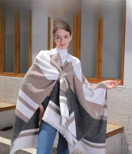Close-up of color-block striped poncho with tassel hem and soft knit texture detail