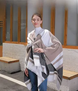 Detailed knit texture of a long striped poncho shawl with delicate fringe edge accents