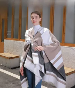 Detailed view of striped knit poncho with fringe hem and soft woven texture