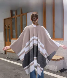 Detail of knit poncho featuring geometric color block patterns and fringe hem design