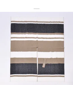 Detailed view of color-block striped knit poncho with fringe edges and tie waist