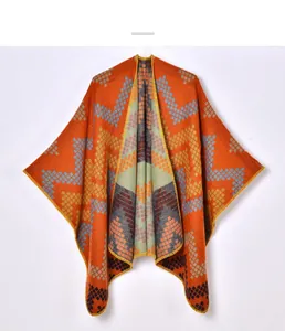 Detail of bohemian geometric jacquard knit pattern on thick warm orange poncho