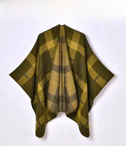 Close-up of the thick green and yellow plaid knit texture and hem detail of the poncho