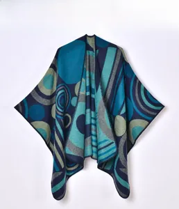 Detailed knit texture of a geometric poncho featuring teal and navy abstract line patterns